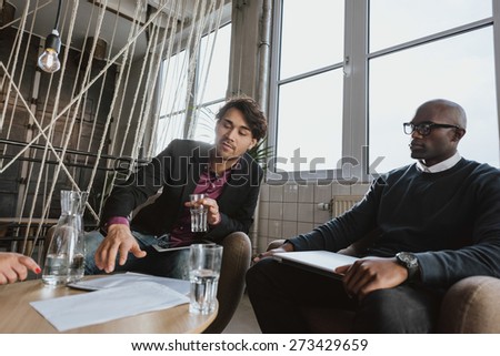 Young executive explaining something to his team in a meeting. Young man discussing business strategy with colleagues during a meeting.