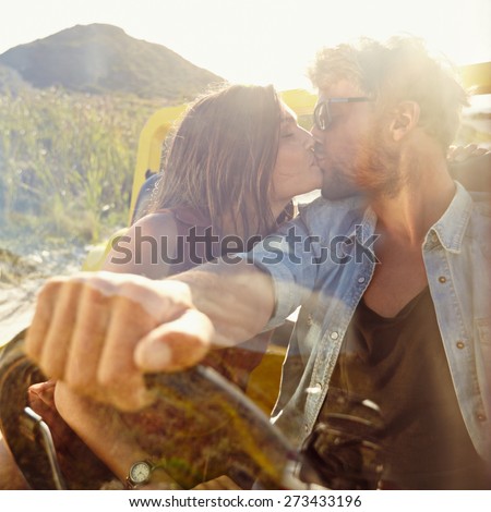 Young couple kissing in the car. Couple in love on road trip having fun.