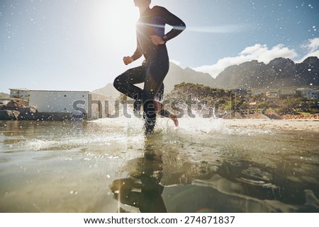 Low angle view of young athlete running into water. Participants running into the water for start of a triathlon race.