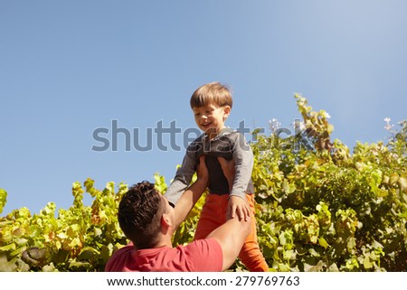 Shot of father lifting his son high in the air. Happy father and son playing outdoors on a sunny day.