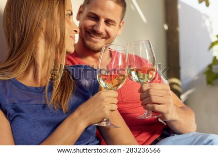 Closeup shot of young man and woman sitting together toasting wine glasses. Couple in love spending romantic time together.