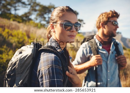 Pretty young woman on a hiking trip with man in the background. Caucasian couple on hike in countryside