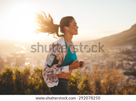 Portrait of beautiful young woman out for a run on a hot sunny day. Caucasian female model jogging outdoors.