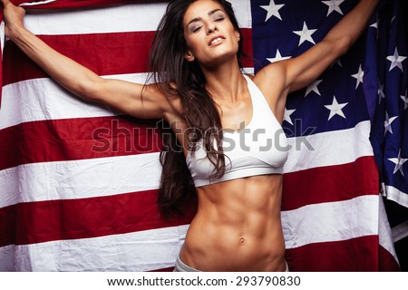 Sporty young woman holding American flag. Fitness female with perfect abs.