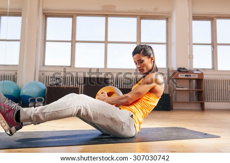 Female fitness model exercising with medicine ball at gym. Young caucasian woman doing crossfit workout.