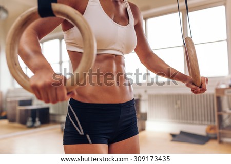 Close up of woman\'s hands holding gymnastic rings. Fit female working out with rings at gym.