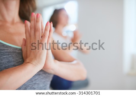 Close up shot of women at yoga class meditating with hands clasped. Female hands in namaste gesture during yoga class.