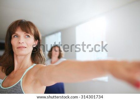 Confident female trainer doing yoga workout at gym. Women practicing yoga at class.