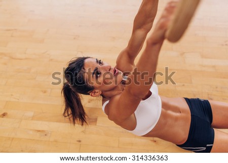 Determined young female model holding gymnast rings. Young woman at gym exercising with rings. Athlete doing pull-ups exercise as crossfit workout.