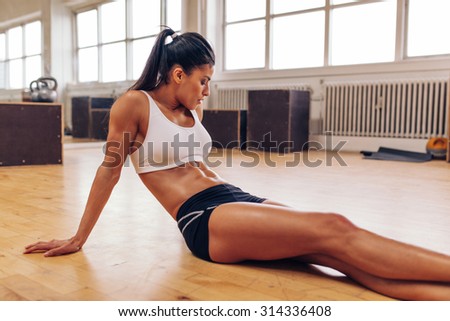 Portrait of muscular young woman relaxing after workout at gym. Fit female athlete taking a break from workout.