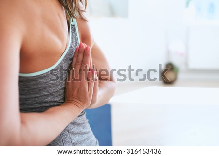 Closeup shot of woman practicing Pashchima Namaskarasana yoga pose at gym. Focus on hands. Reverse prayer Pose.