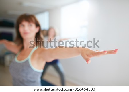 Woman stretching her arms at yoga class. Fitness trainer performing yoga in warrior pose. Virabhadrasana. Focus on hand.
