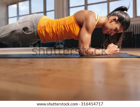 Young woman doing pilates, working on abdominal muscles. Muscular female doing core workout in the gym.