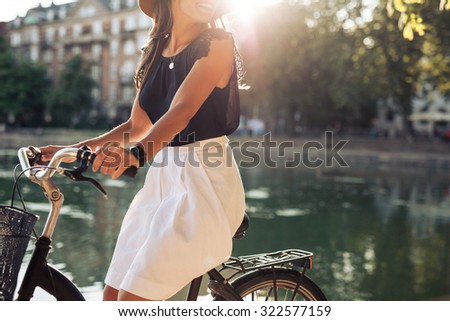 Cropped shot of young woman cycling by a pond. Woman on a summer day riding her bicycle.