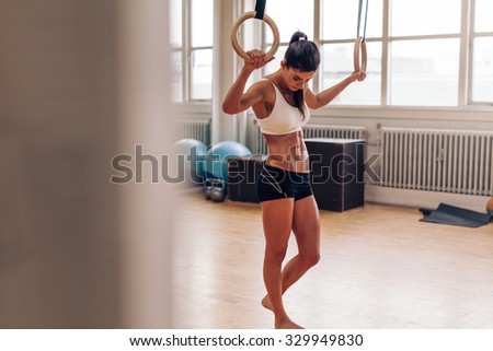 Muscular woman relaxing after workout at gym.  Fitness woman taking break from dipping exercise. Crossfit dip ring exercise.