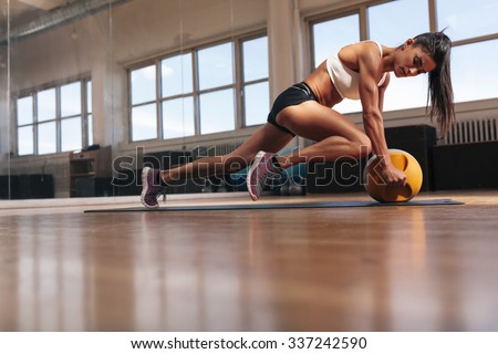 Woman doing intense core exercise on fitness mat. Muscular young woman doing workout at gym.