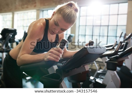 Fitness woman on bicycle doing cardio workout at gym. Fit young female exercising on gym bike.