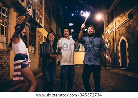 Shot of a young people playing with sparklers at night. Best friends hanging out at night and celebrating 4th of july outdoors.