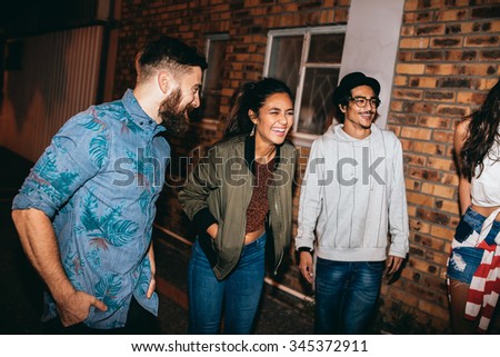 Multi-ethnic group of friends chatting and laughing at the party. Young men and women hanging out together at rooftop party.