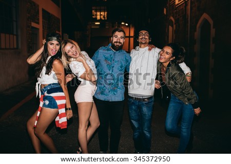 Portrait of young men and women looking at camera laughing. Multiracial group of young friends hanging out in outdoor party.