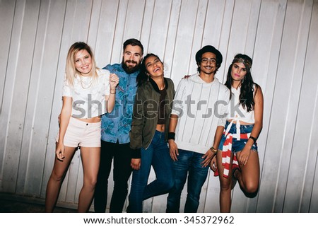 Portrait of cheerful young friends standing together outdoors. Multiracial young people hanging out at night.