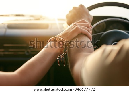 Close up shot of loving couple traveling by car and holding hands. Focus on hands of man and woman in a road trip.