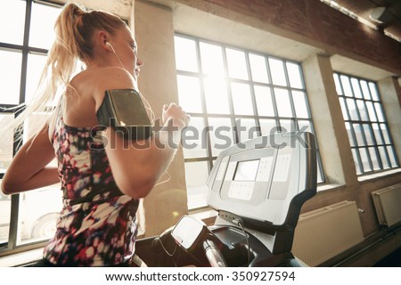 Young focused female working out at gym jogging on a treadmill. Fitness woman doing running exercise in the health club.