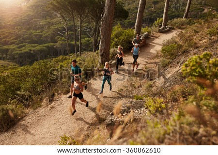 Group of runners in a cross country race. Young people running in nature. Trail running workout.