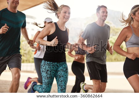 Group of happy young friends running together. Running club members exercising.