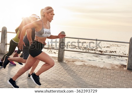 Portrait of young people running on seaside promenade. Group of women running marathon.