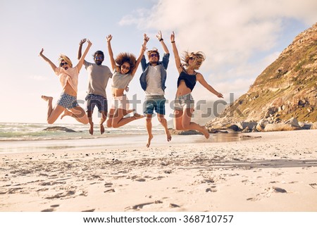 Group of friends together on the beach having fun. Happy young people jumping on the beach. Group of friends enjoying summer vacation on a beach.