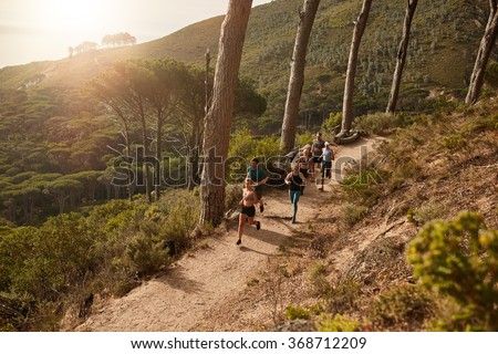 High angle view of running club group training on mountain trails. Group of fit athletes running on mountain path.