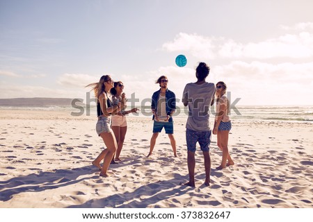 Group of young people playing with ball at the beach. Young friends enjoying summer holidays on a sandy beach.