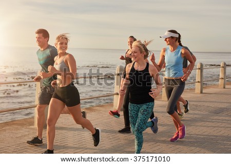 Portrait of young people running by the sea in morning, Healthy young men and women doing running workout.