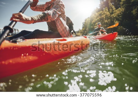 Cropped image of woman kayaking with a man in background. Couple canoeing in a lake on a summer day.