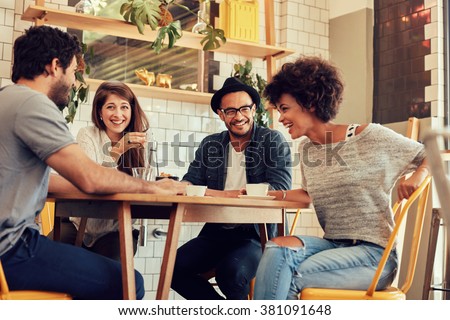 Portrait of cheerful young friends having fun while talking in a cafe. Group of young people meeting in a cafe.