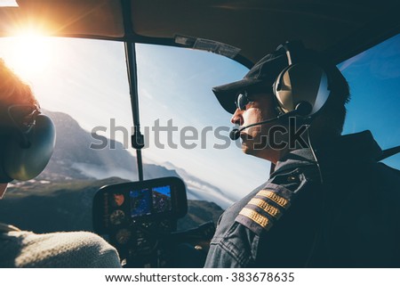 Man and woman pilots flying a helicopter on a sunny day. Inside shot of a helicopter.