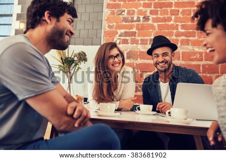 Group of young friends hanging out at a coffee shop. Young men and women meeting in a cafe having fun.
