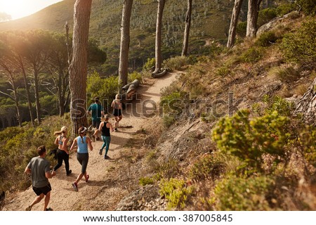 Group of young people trail running on a mountain path. Runners working out in beautiful nature.