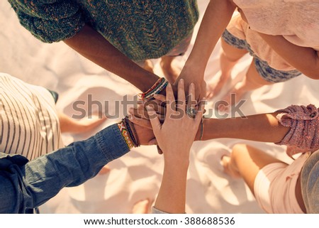 Group of young men and women showing unity. Group of young friends putting their hands together at the beach.