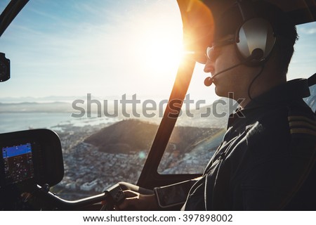 Close up of a male pilot flying a helicopter over city of Cape town on sunny day