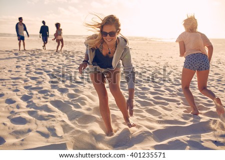 Young women running race on the beach. Group of young people playing games on sandy beach on a summer day. Having fun on the beach.