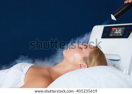Close up shot of young caucasian woman getting laser facial treatment in cosmetology clinic. Female receiving local cryotherapy therapy.