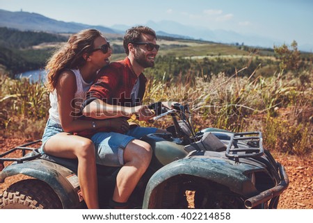 Man and woman having fun on an off road adventure. Couple riding on a quad bike in countryside on a summer day.