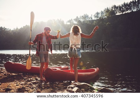 Young man helping woman to step into the kayak. Couple going for a canoe ride in the lake.