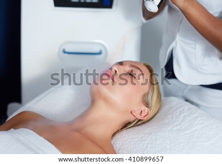 Attractive young woman getting local cryotherapy therapy at cosmetology clinic. Applying cold nitrogen vapors to the face of woman.