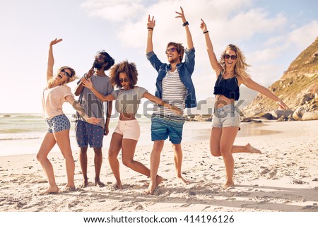 Portrait of excited young friends standing on the beach. Multiracial group of friends enjoying a day at beach.