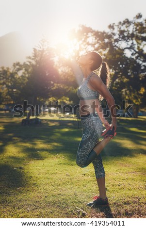 Outdoor shot of fit young woman in sportswear stretching her legs before a run. Female athlete warning up and getting ready for her fitness training.