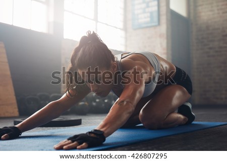 Shot of a young woman doing yoga on the gym floor. Muscular female doing stretching workout at health club.