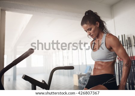 Fitness woman sitting on a bicycle in gym.  Fit young female exercising on gym bike.